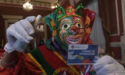 Pepino, personaje del carnaval paceño, muestra su carnet de vacunación.