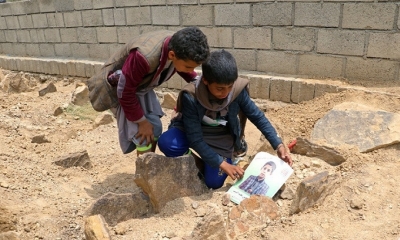 Dos menores con la foto de un niño que murió en el autobús que atacó la coalición liderada por Arabia Saudita, Saada, Yemen