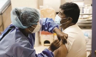 Una persona es vacunada por personal médico. 