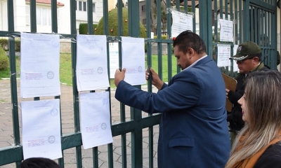 Un oficial de diligencia del juzgado pega la notificación del fallo en puertas del Tribunal Supremo Electoral.
