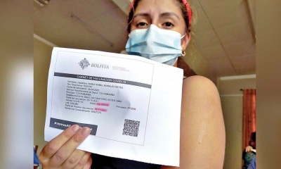 Una mujer muestra su carnet de vacunación contra la COVID.