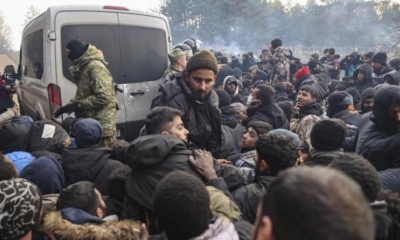 Refugiados y migrantes se agolpan para recibir ayuda humanitaria distribuída por soldados bielorrusos en un campo en la frontera con Polonia .
